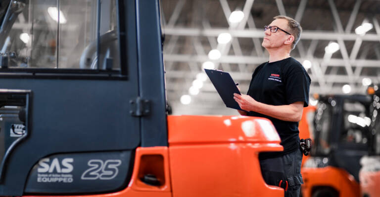 Operator supervising the condition of the mounting brackets of a group of Toyota forklifts